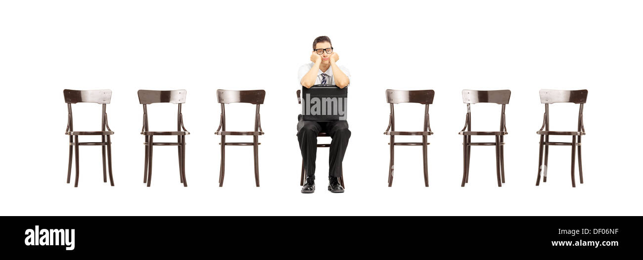 Annoiato Uomo con valigetta in pelle seduta su una sedia di legno in attesa per il colloquio di lavoro Foto Stock