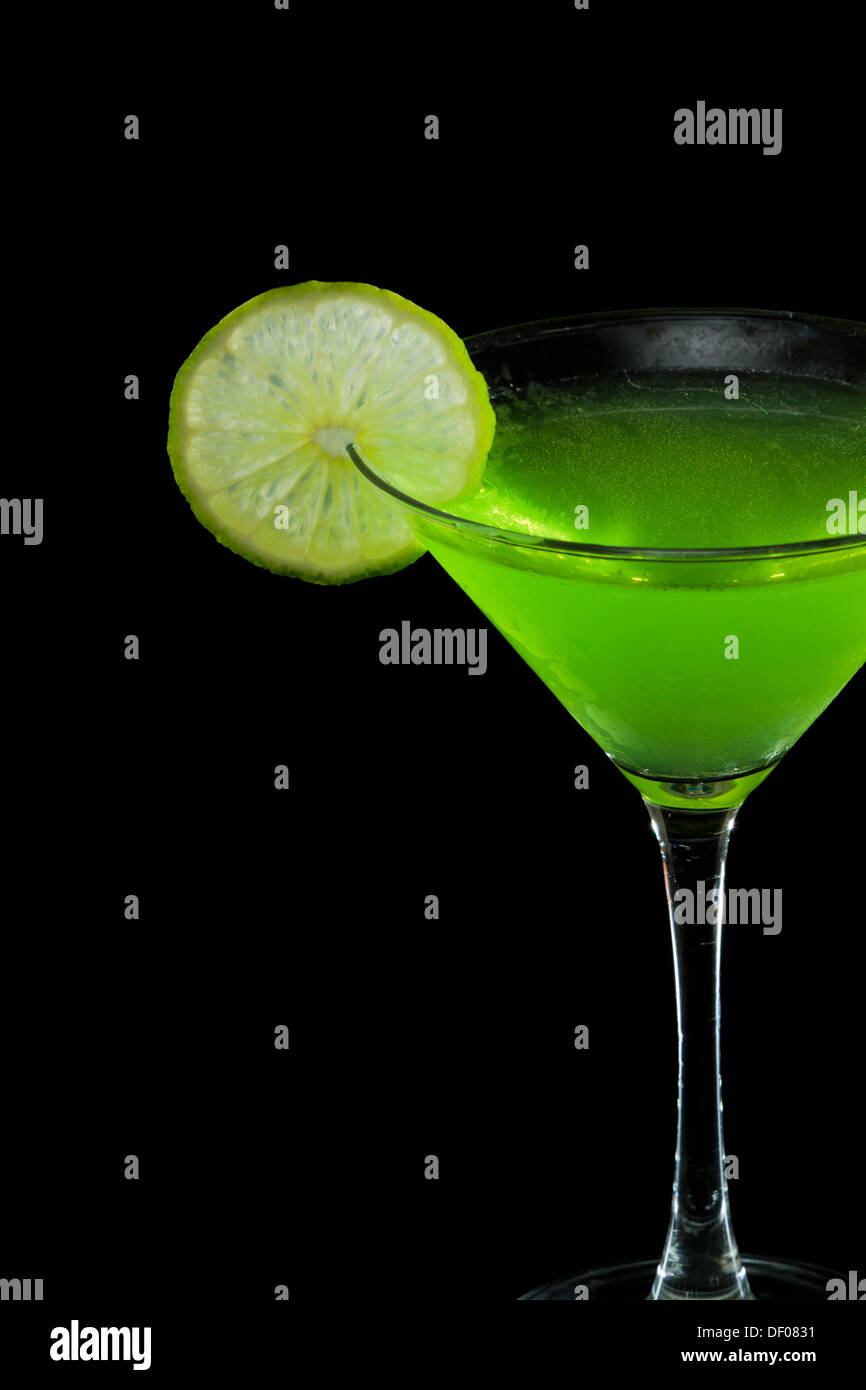 Il neon verde martini servito su uno sfondo nero guarnito con un lime sul bordo Foto Stock