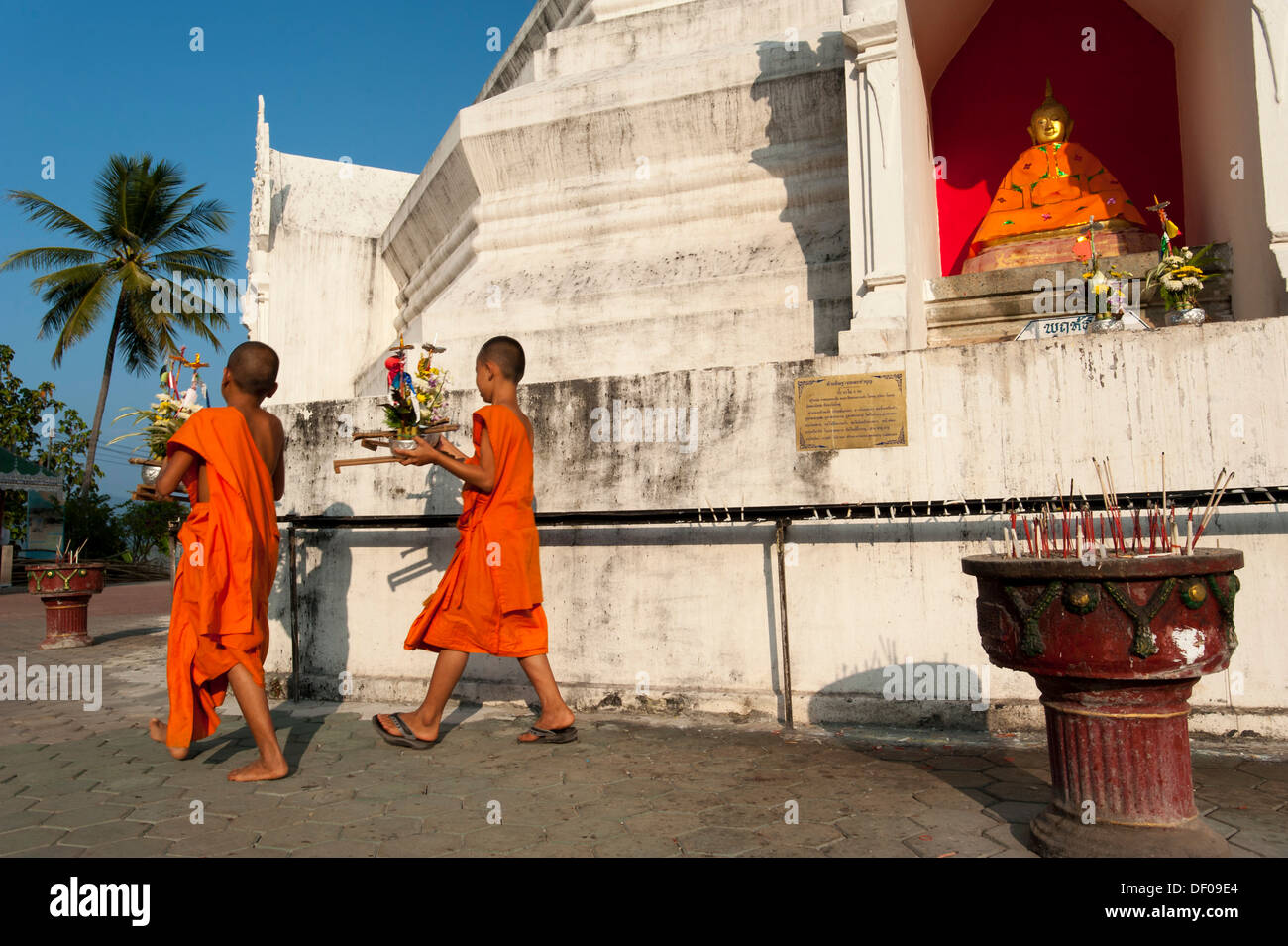 I giovani monaci buddisti con offerte di fronte una pagoda o Chedi, complesso tempio di Wat Phra That Doi Kong Mu, Mae Hong Son Foto Stock