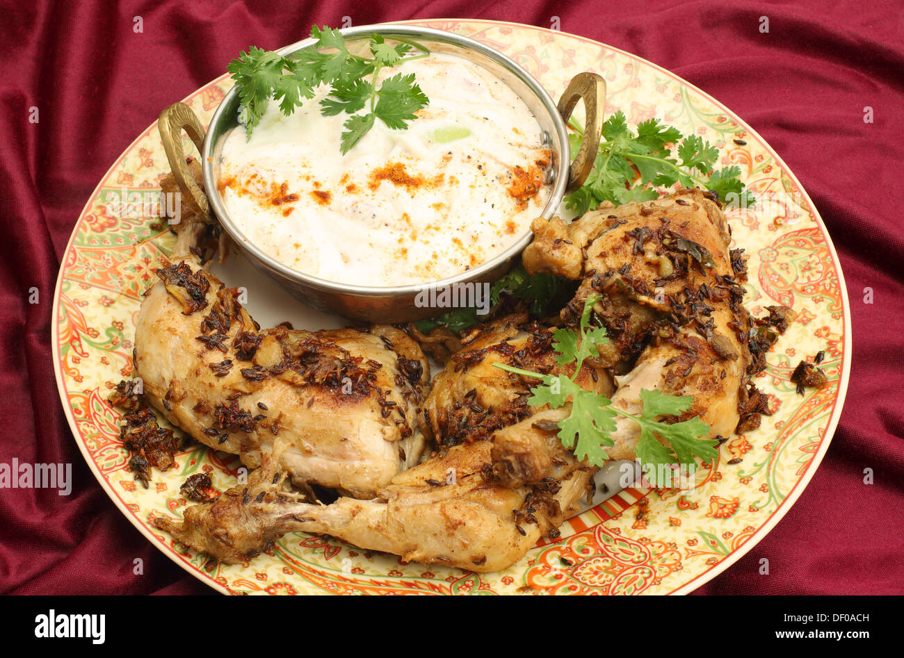 In casa jeera fritti (cumino) pollo serviti con raita di cetriolo e una foglia di coriandolo guarnire. Foto Stock