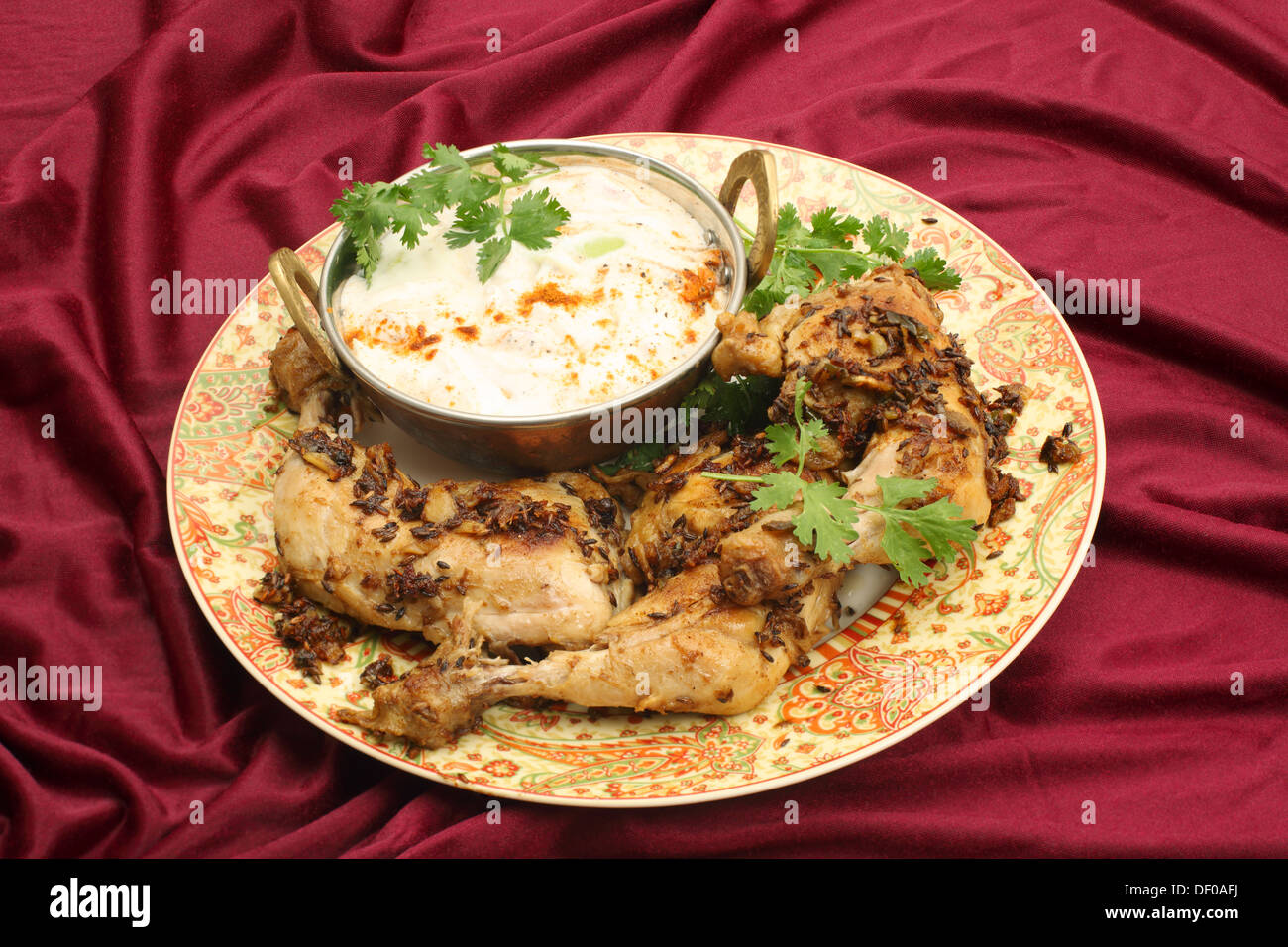 In casa jeera fritti (cumino) pollo serviti con raita di cetriolo e una foglia di coriandolo guarnire. Foto Stock