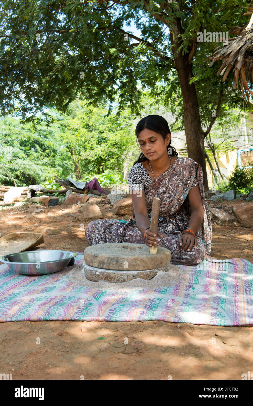 Rurale villaggio indiano donna utilizzando pietre Quern per macinare il miglio di dito seme / Ragi semi in Ragi farina. Andhra Pradesh. India Foto Stock