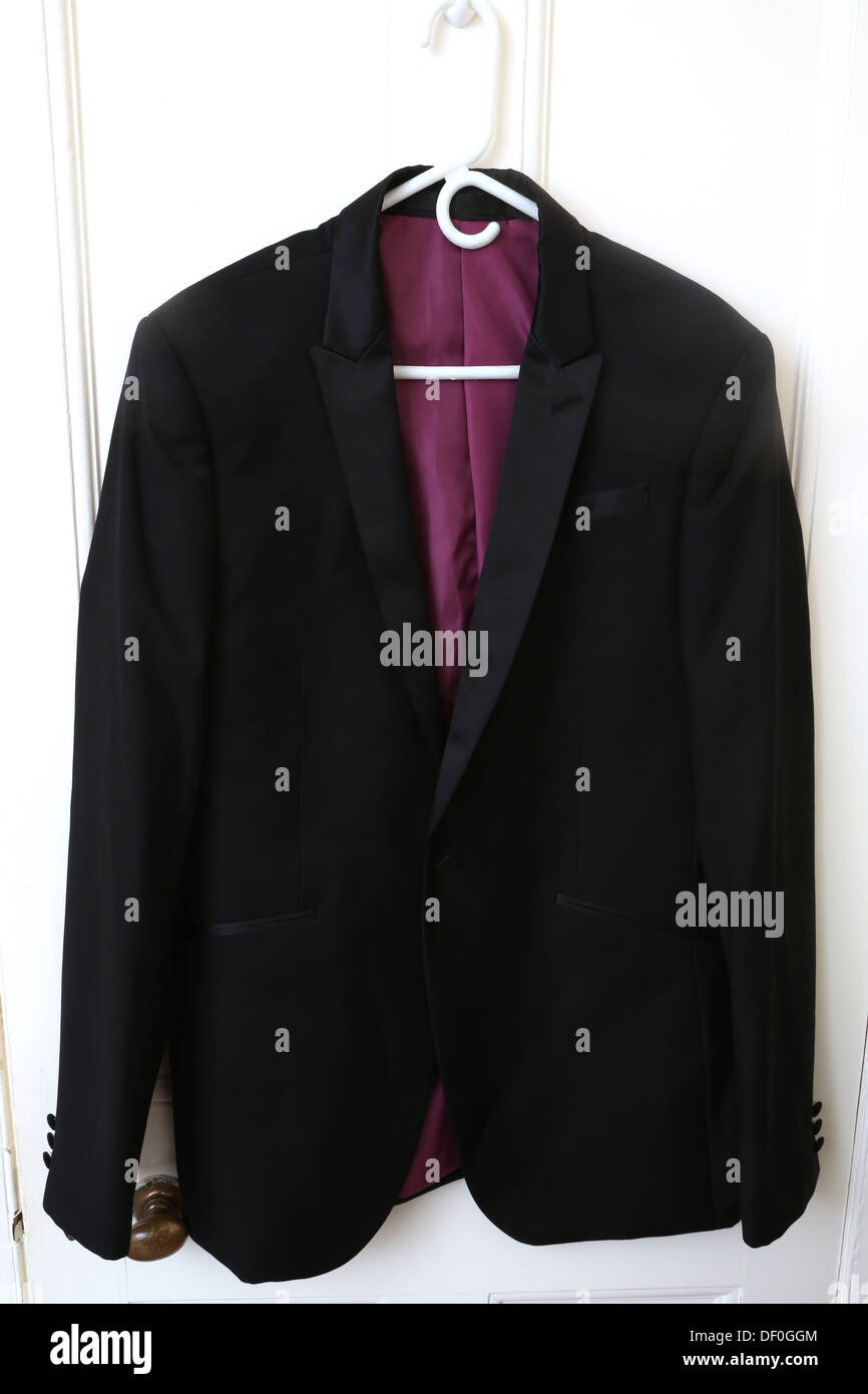 Cena nero giacca con collare stretto e rivestimento rosa appeso sulla porta Foto Stock