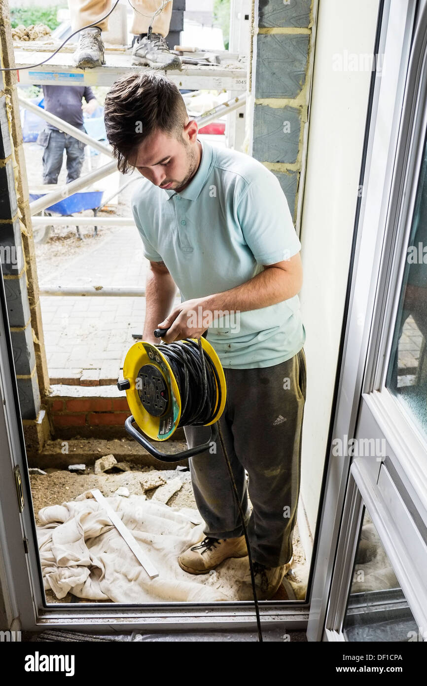 Un lavoratore utilizzando un cavo di prolunga tamburo in un recentemente costruita porta di una casa. Foto Stock