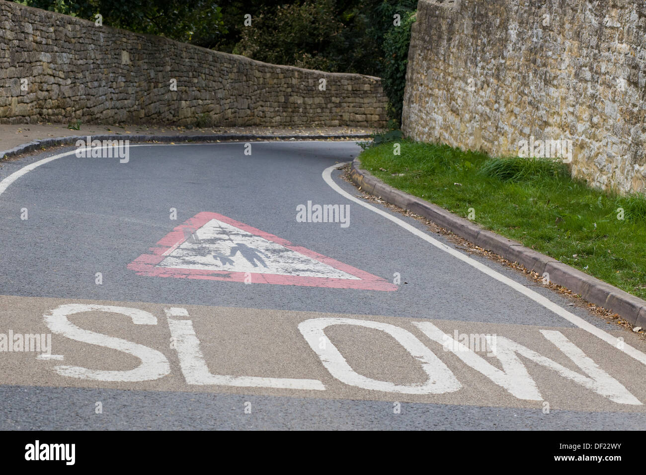 Piegare in una strada con Cotswold muro di pietra con lenta su di esso Foto Stock
