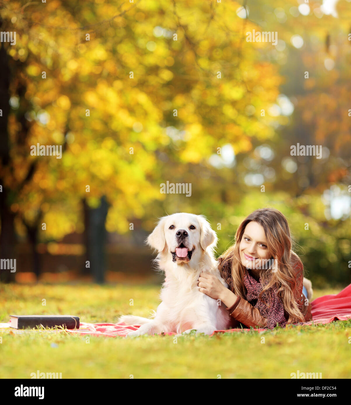 Giovani femmine sdraiato con il suo cane recuperatore in un parco Foto Stock