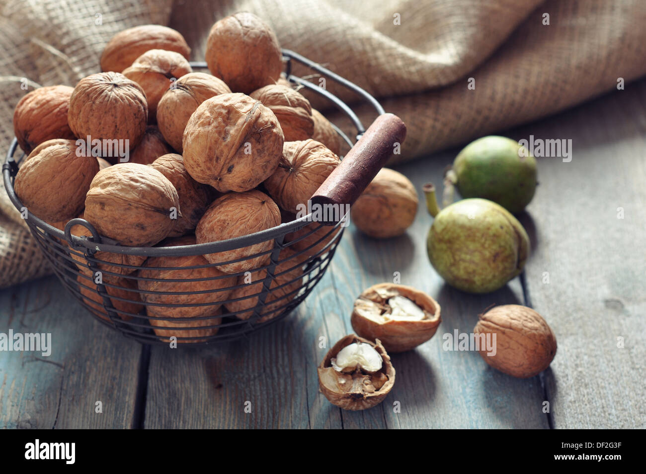 Intero e noci tritate in cestello sul vecchio sfondo di legno Foto Stock