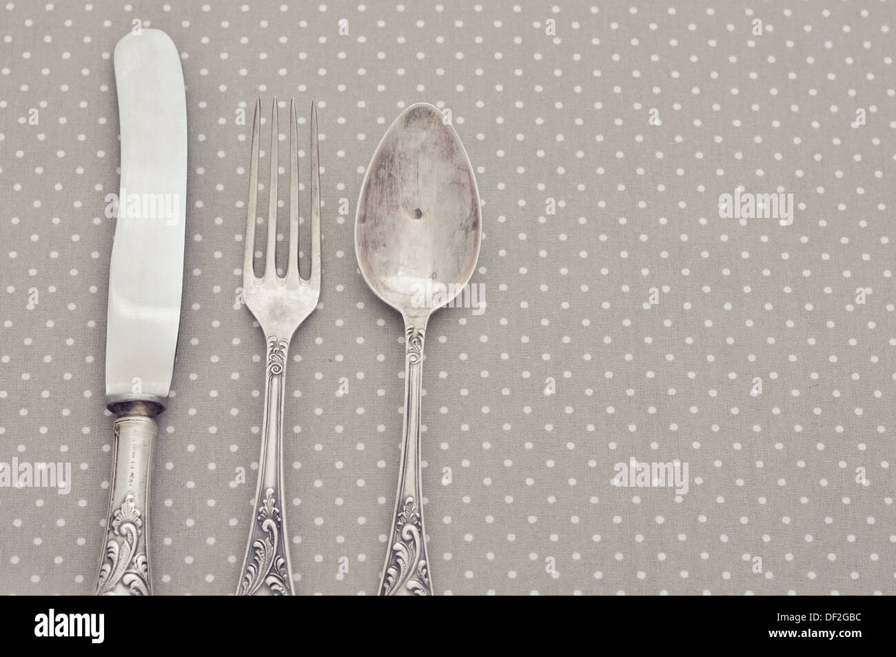 Forchetta, cucchiaio e il coltello sulla luce polka dot sfondo. Foto Stock