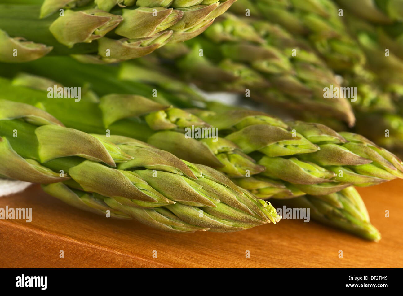 Primo piano della materie asparagi verdi teste (messa a fuoco selettiva, messa a fuoco sulla testa di asparagi nella parte anteriore) Foto Stock