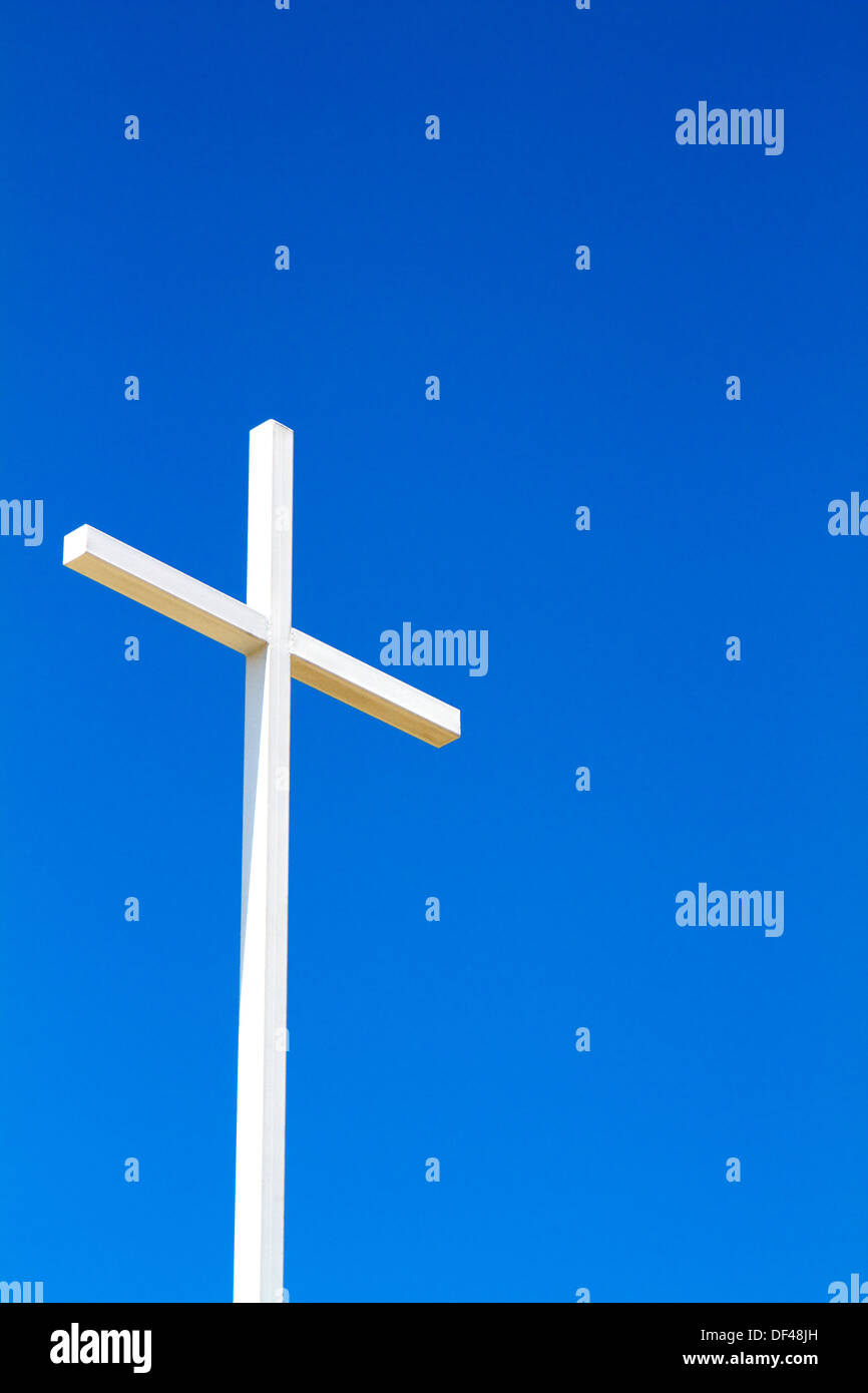 Bianco acciaio fabbricata una Croce Cristiana si staglia contro un cielo blu chiaro. Foto Stock