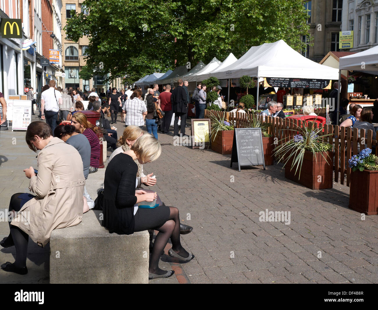 La pausa pranzo per chi lavora in ufficio su St Ann's Square con le bancarelle del mercato a Manchester REGNO UNITO Foto Stock