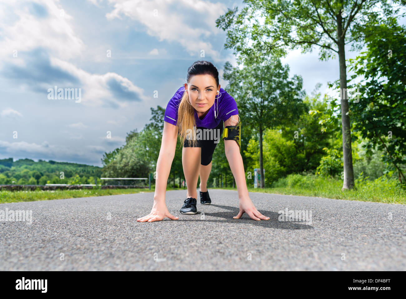 Urban sport - giovane donna sta facendo il riscaldamento prima di eseguire in greenfield su un giorno di estate Foto Stock