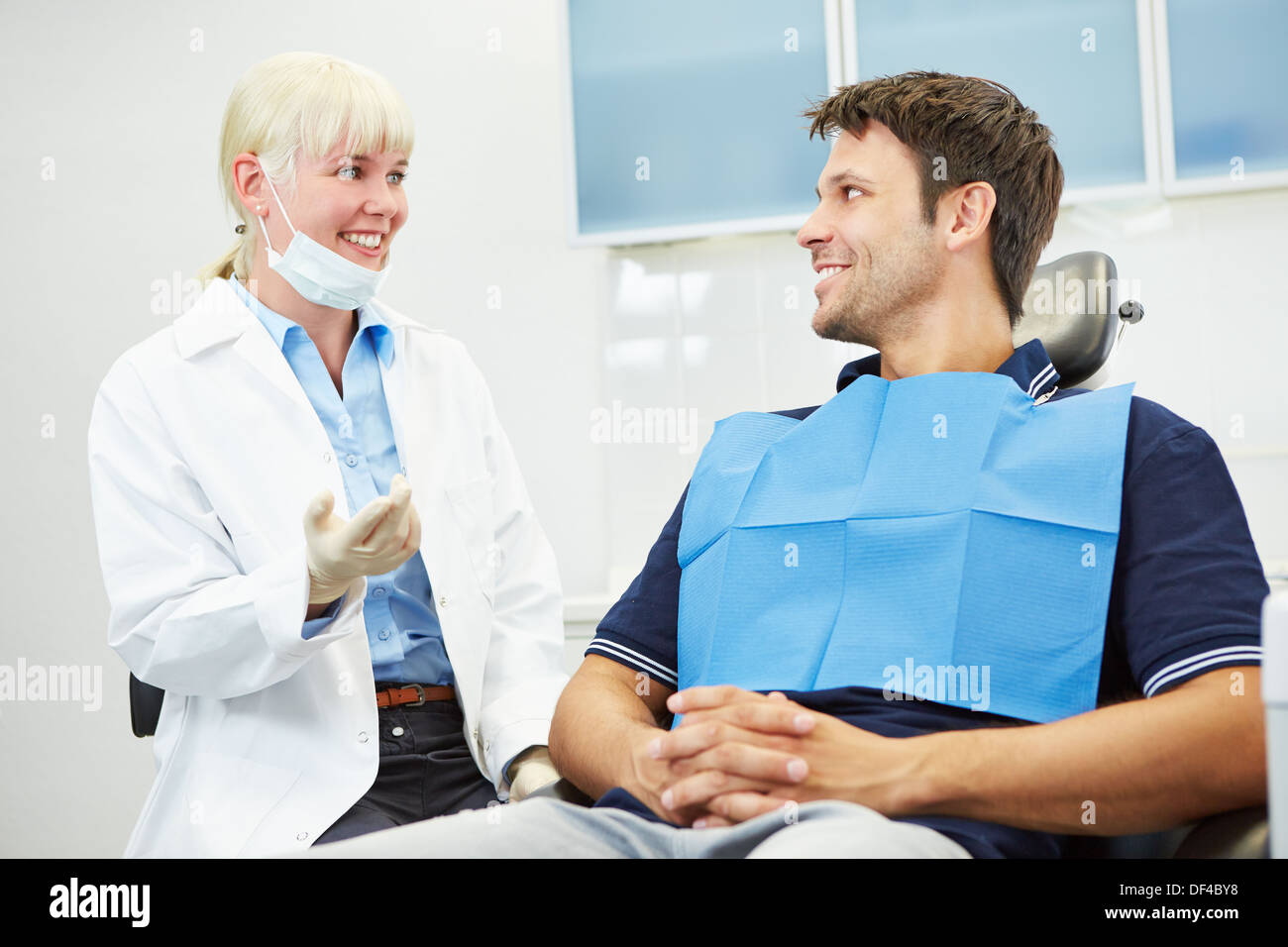Dentista femmina di parlare con un paziente su sedia dentale Foto Stock