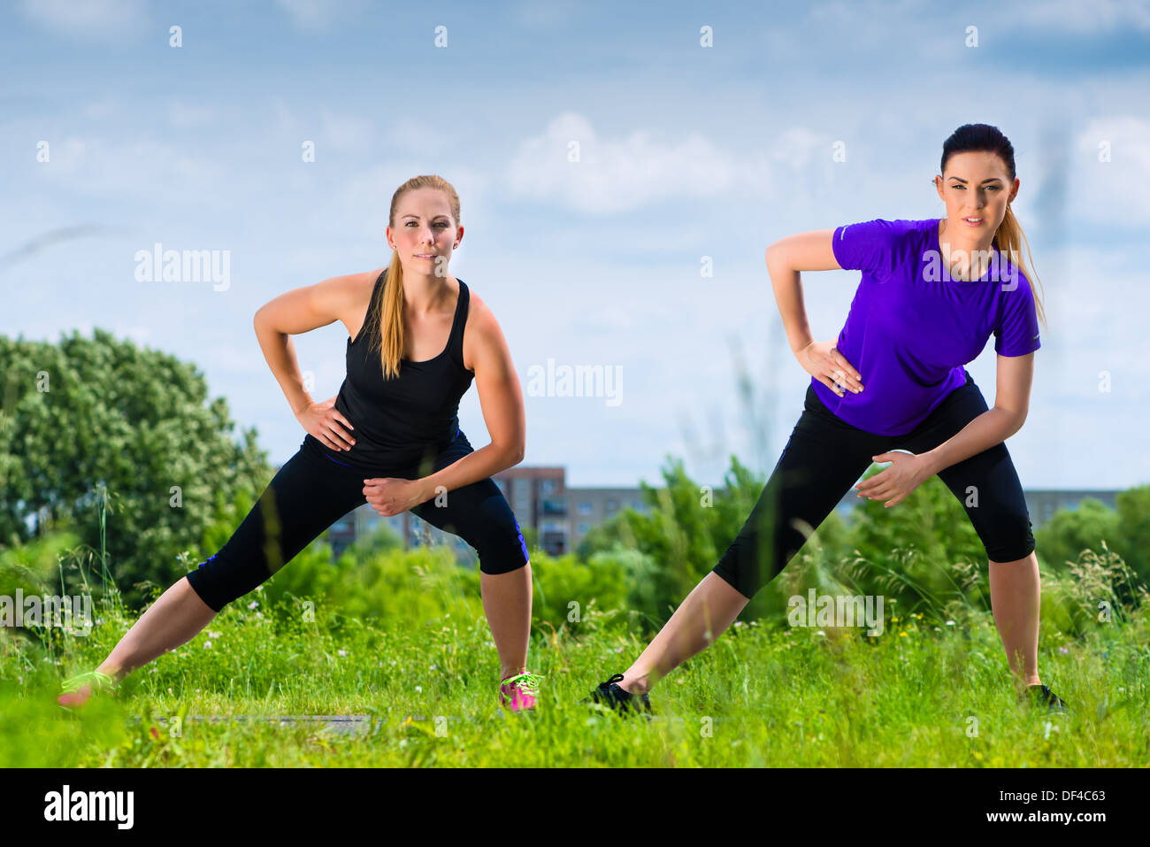 Urban sport - Giovani donne facendo il riscaldamento insieme prima esecuzione in greenfield su un giorno di estate Foto Stock