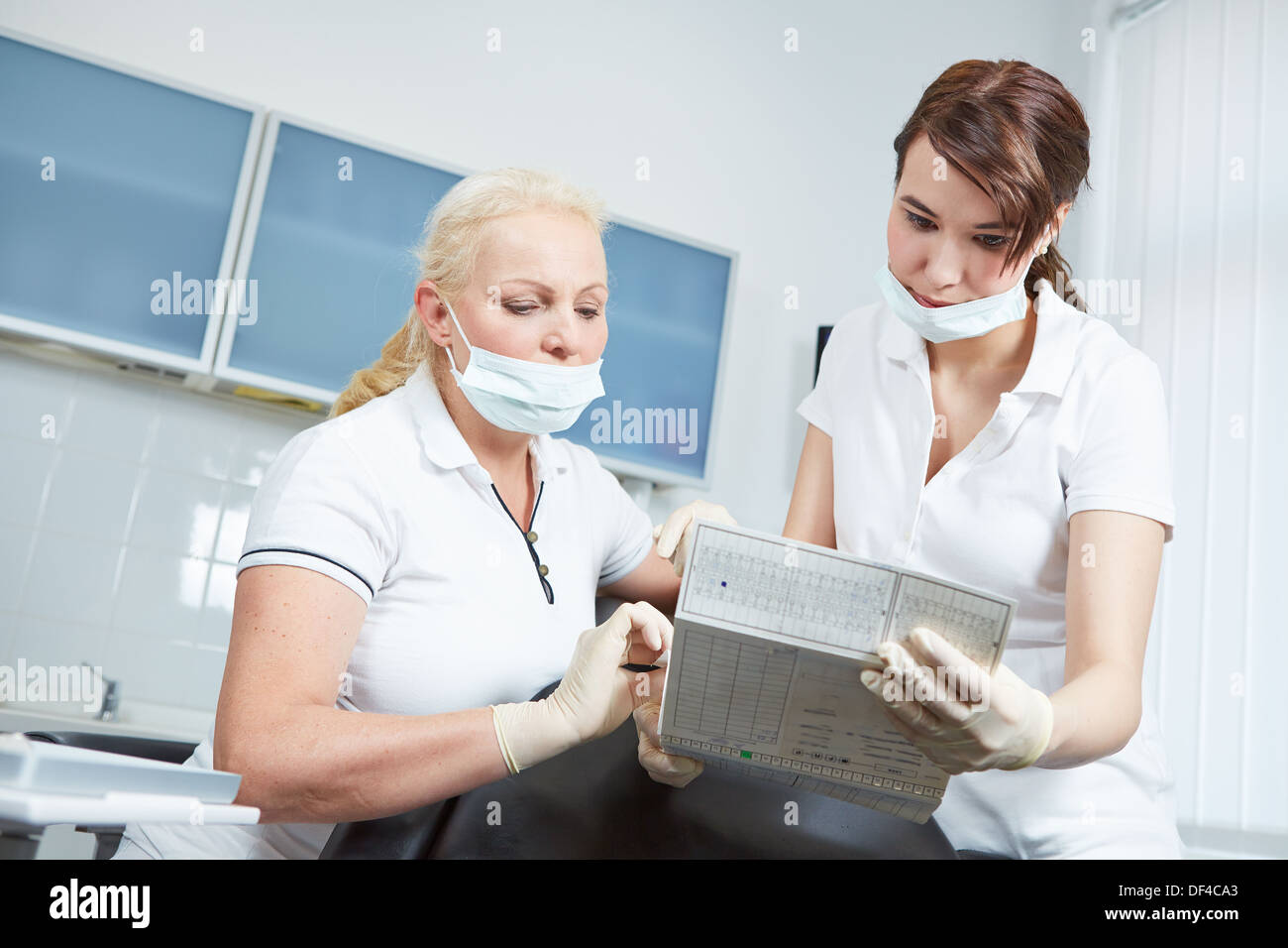 Dentista e assistente medico di lettura dei record di un paziente prima del trattamento Foto Stock