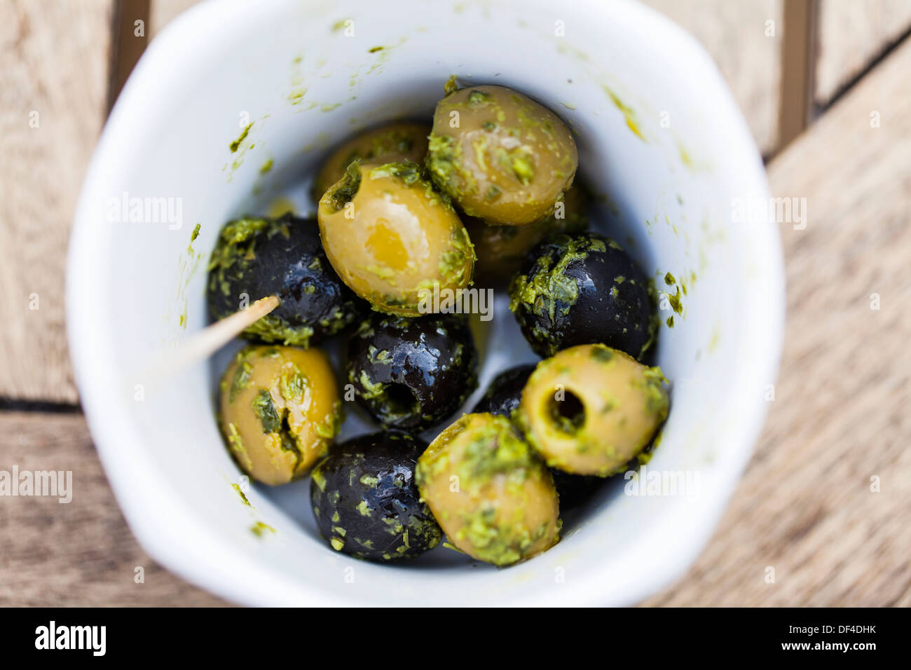 Cerca gustose olive nere e verdi in una piccola ciotola con un olio e condimento alle erbe Foto Stock