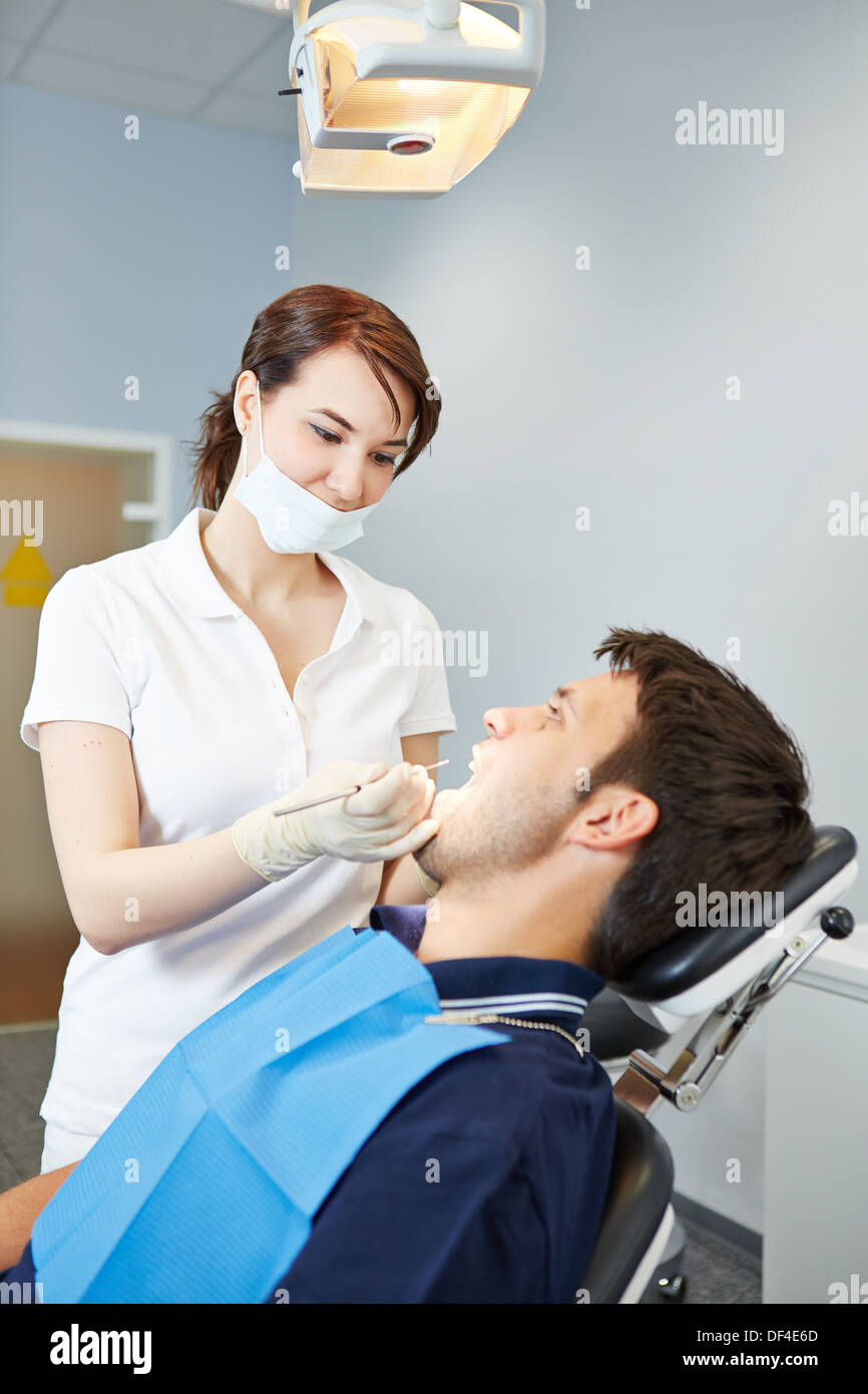 Paziente di sesso maschile in esame dentale con femmina dentista Foto Stock