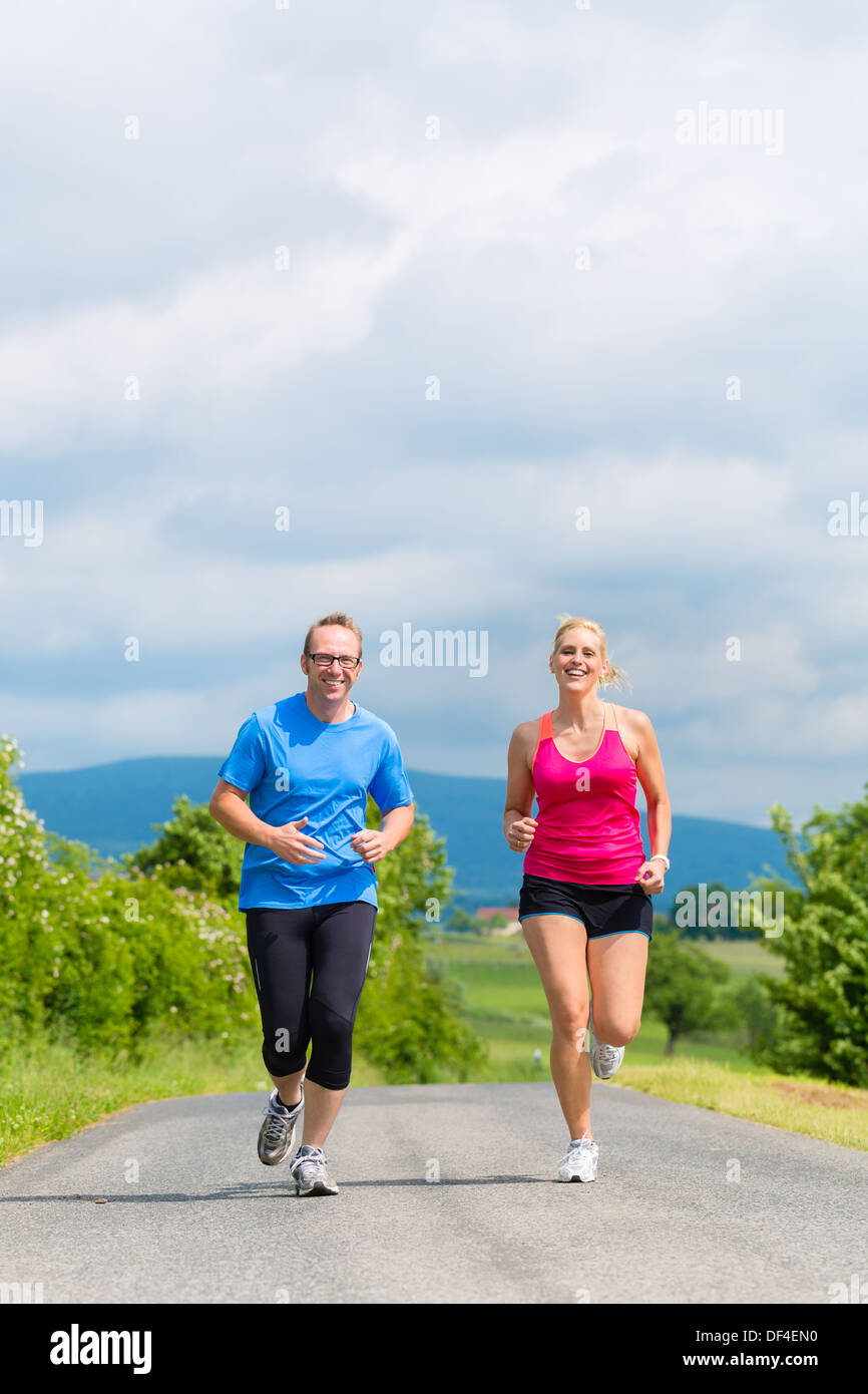 Giovane uomo e donna facendo jogging o outdoor sport per il fitness su strada rurale Foto Stock