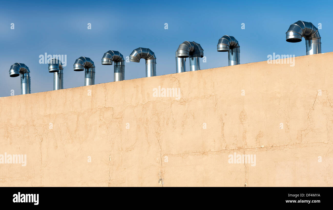 Una panoramica di immagini editoriale di chrome bocchette sul tetto cielo blu e un colore neutro parete Foto Stock