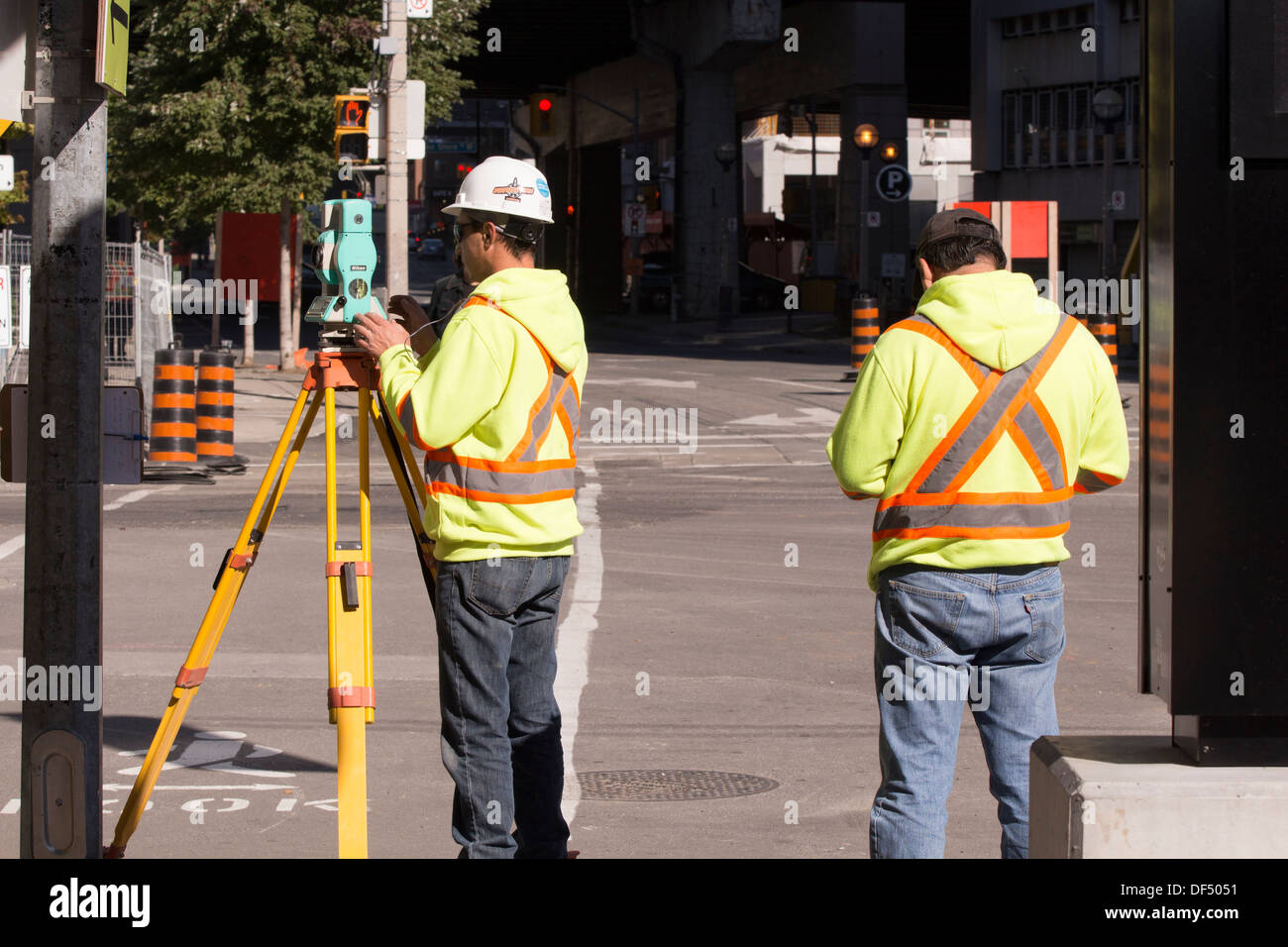 Geometra teodolite di regolazione in corrispondenza di strada in costruzione sito nel centro di Toronto Foto Stock