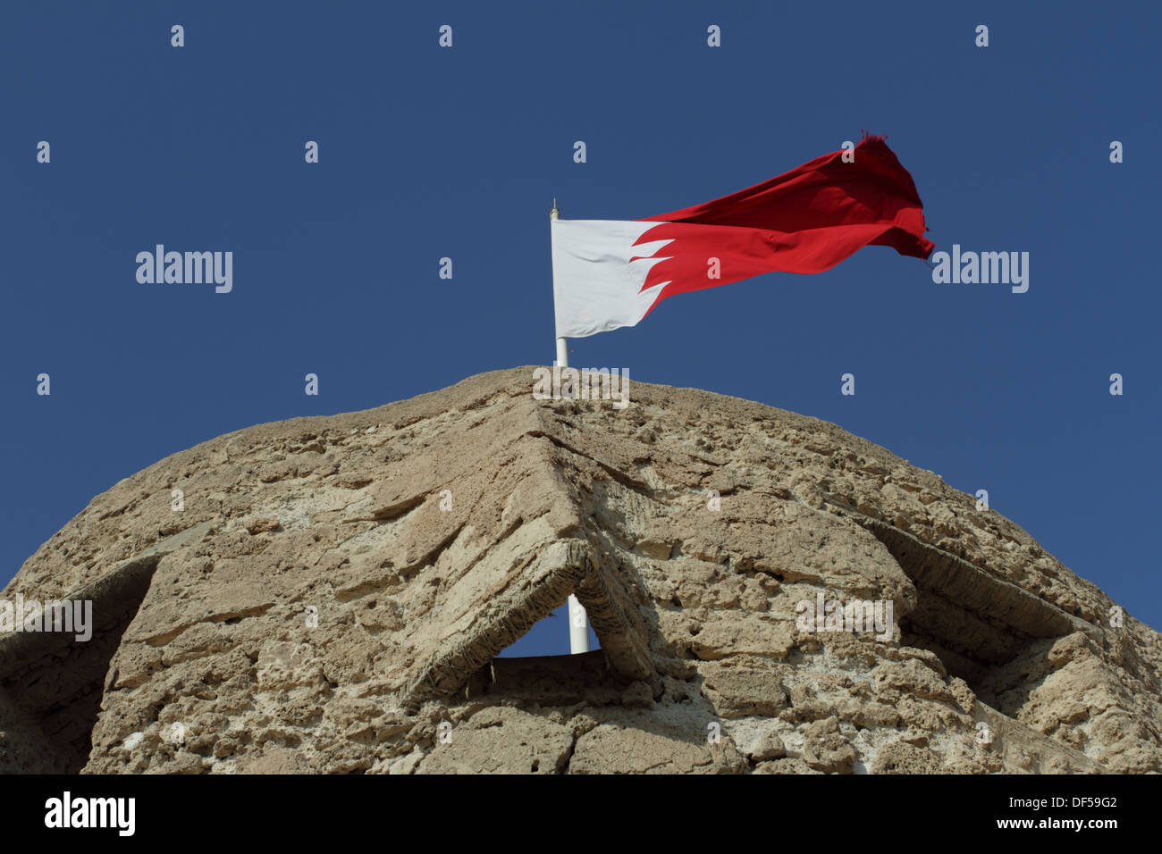 La torretta del Forte di Arad in Muharraq, Regno del Bahrein, con il Bahrain battenti bandiera Foto Stock