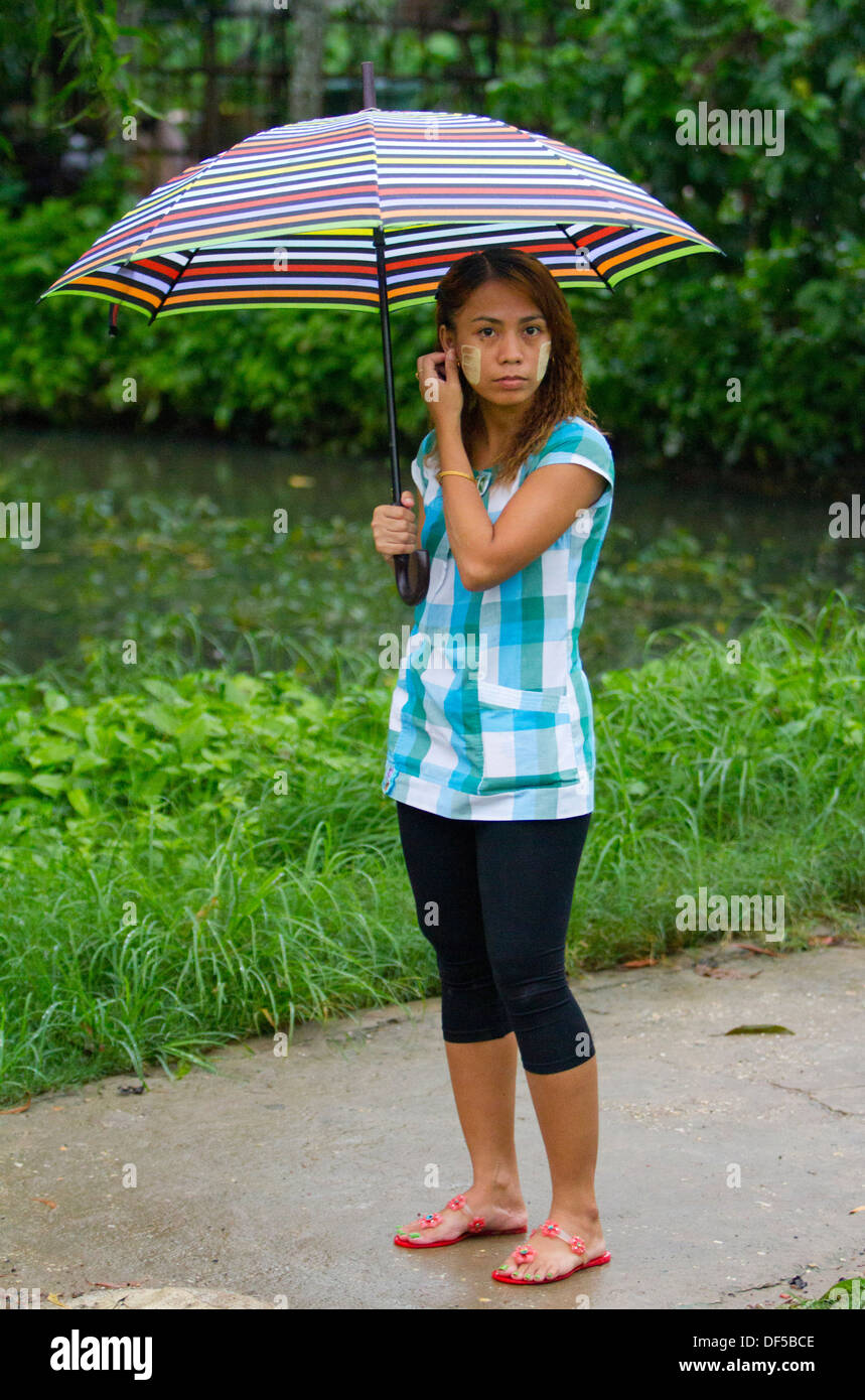 Una donna si trova di fronte a una stazione ferroviaria a Yangon, Birmania. Foto Stock