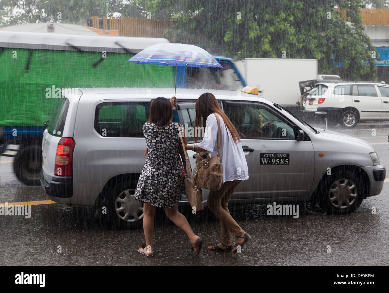 La gente a piedi sotto la pioggia a Yangon, Birmania. Foto Stock