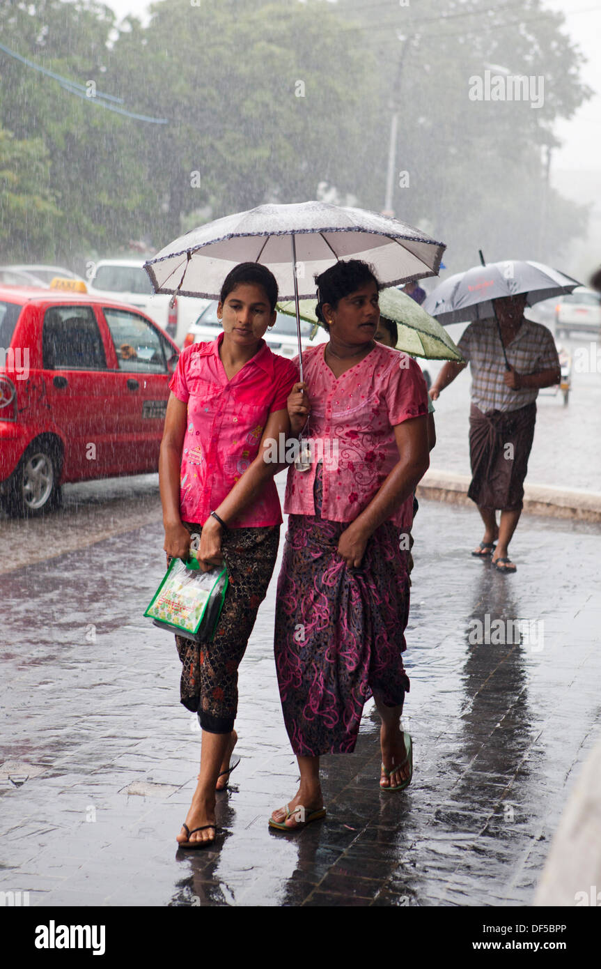 La gente a piedi sotto la pioggia a Yangon, Birmania. Foto Stock