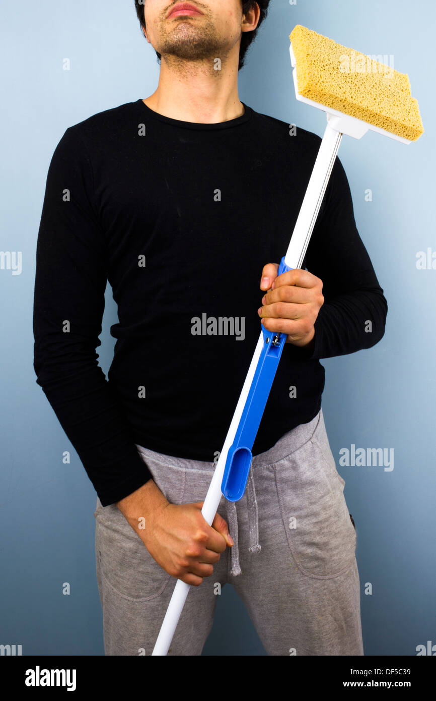 Giovane uomo tenendo un mop e in piedi in un orgoglioso pongono Foto Stock