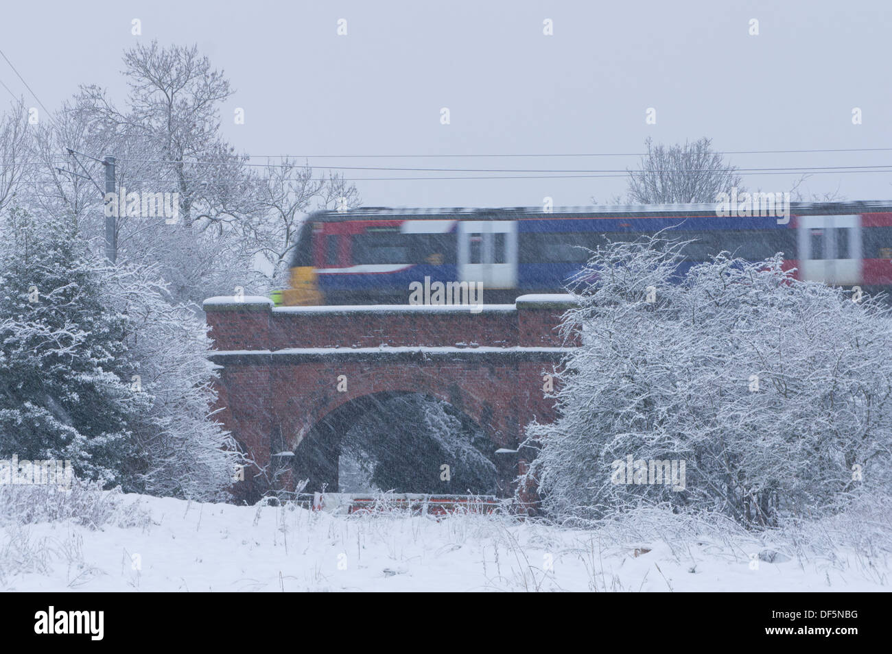 La neve è caduta & locale treno passeggeri è attraversando il ponte, che corre lungo la linea Wharfedale su nevoso inverno giorno - Baildon, West Yorkshire, Inghilterra, Regno Unito. Foto Stock