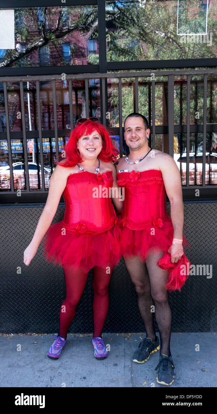 Coppia sorridente indossando identici abiti rossi & scarpe da corsa a prepararsi per la NYC Hash House Harriers annuale abito rosso carità eseguire set per iniziare in corrispondenza di un angolo della 50th Street & 10th Avenue alle 3 del pomeriggio di sabato 28 settembre New York City USA Foto Stock