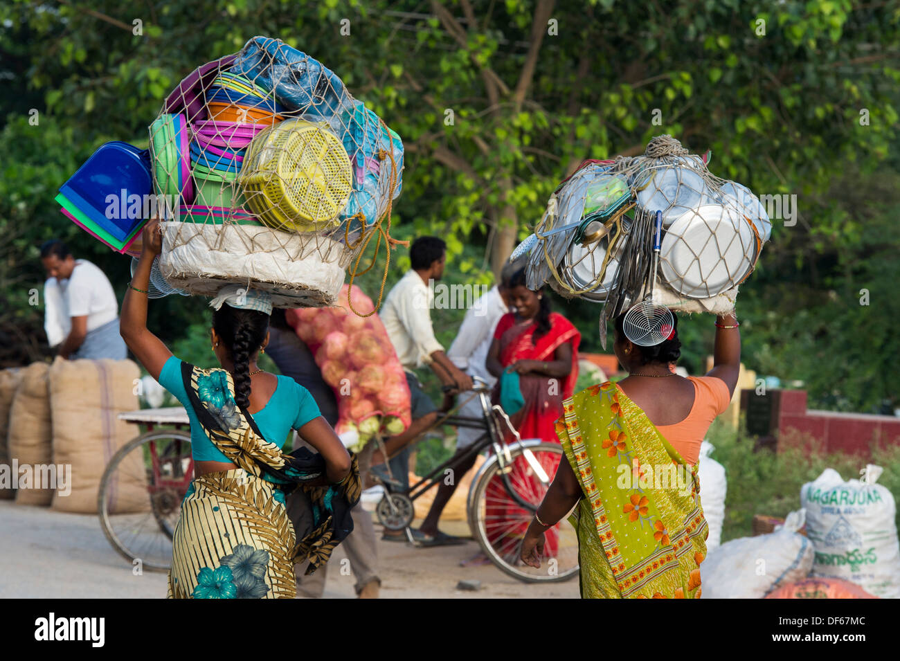 Le donne indiane che effettuano il trasporto di merci sulle loro teste per mercato. Puttaparthi, Andhra Pradesh, India Foto Stock