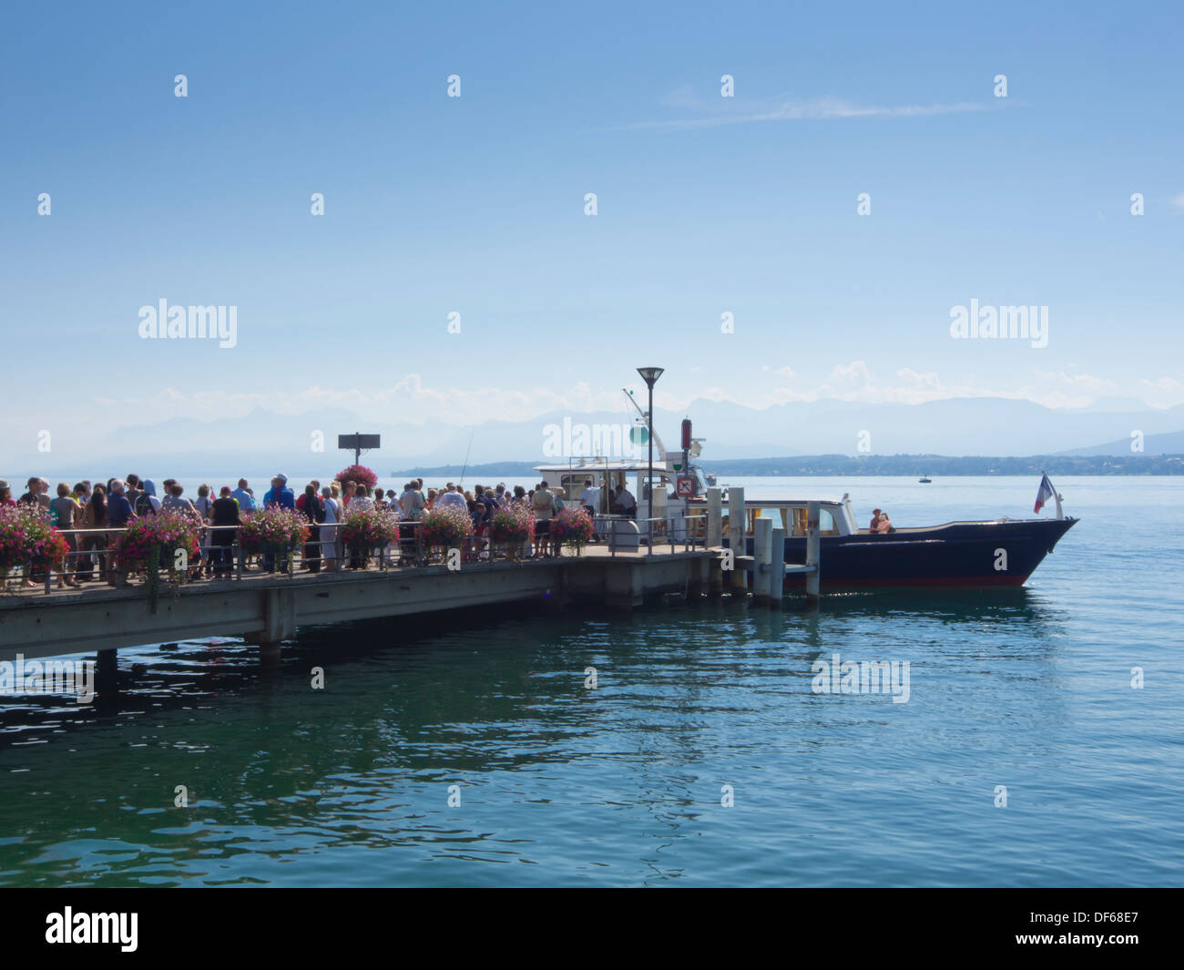 Nyon, una cittadina svizzera sulle rive del Lago di Ginevra, fiore decorate pier con persone in lista per una gita sul lago Foto Stock