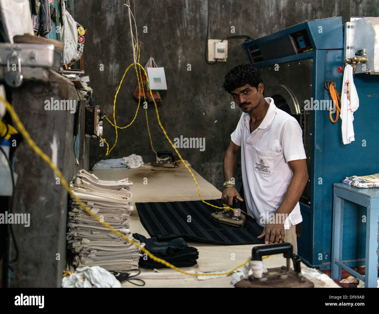 Uomo indiano a stirare a Mahalaxmi Dhobi Ghat o lavanderia a Mumbai India Foto Stock