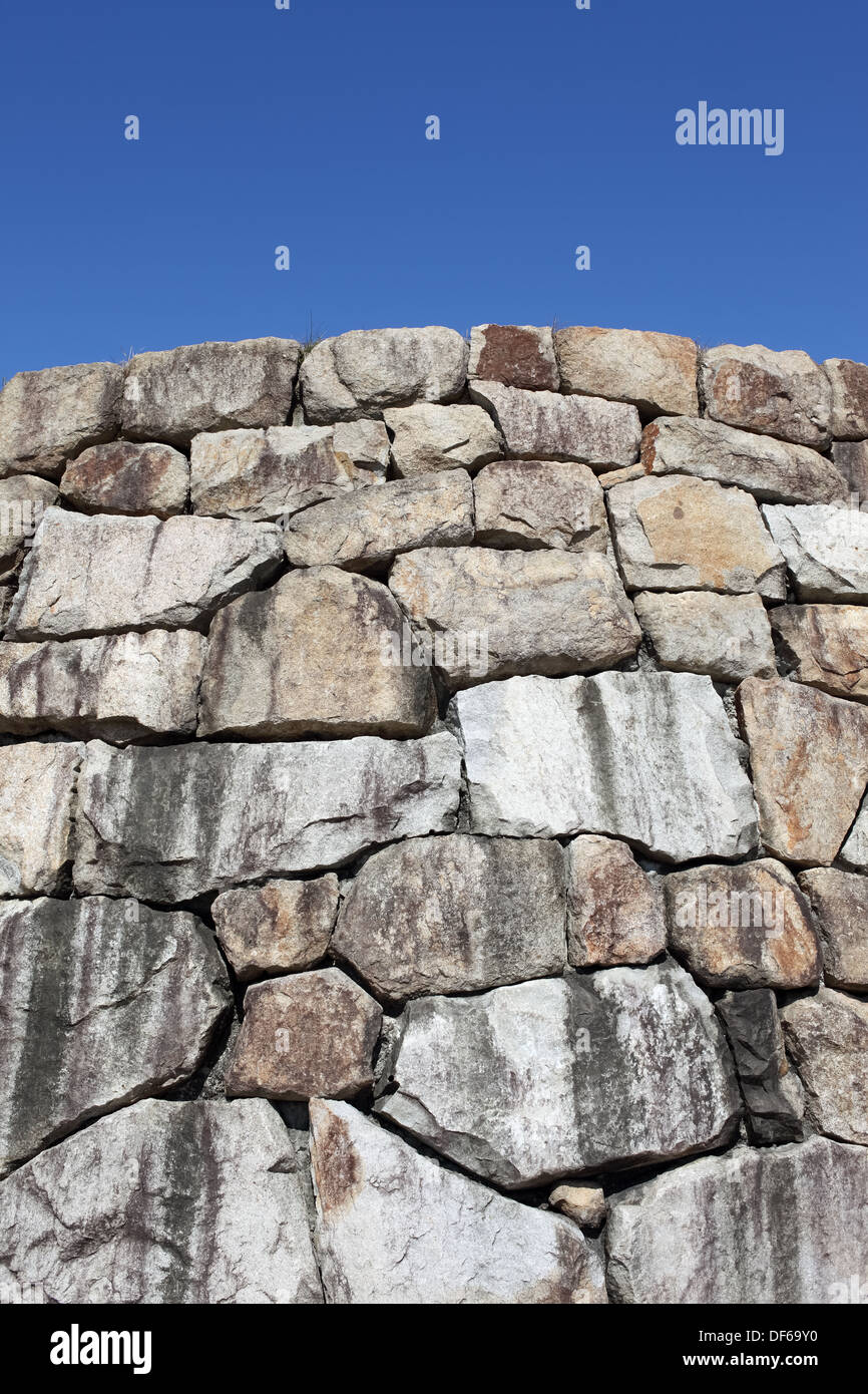 Il vecchio muro di pietra texture, contro il cielo blu chiaro Foto Stock