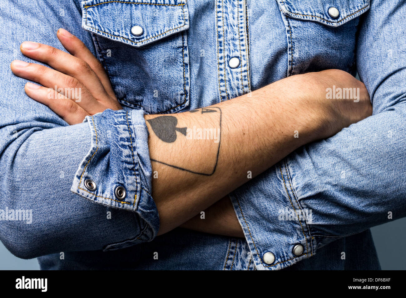 Vicino sul giovane di bracci ripiegati con asso di picche tattoo Foto Stock