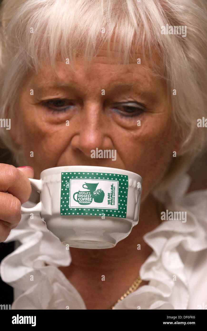 Donna anziana con una tazza di caffè a macmillan cancer support mattina caffè, Farnham, Surrey, Regno Unito. Foto Stock