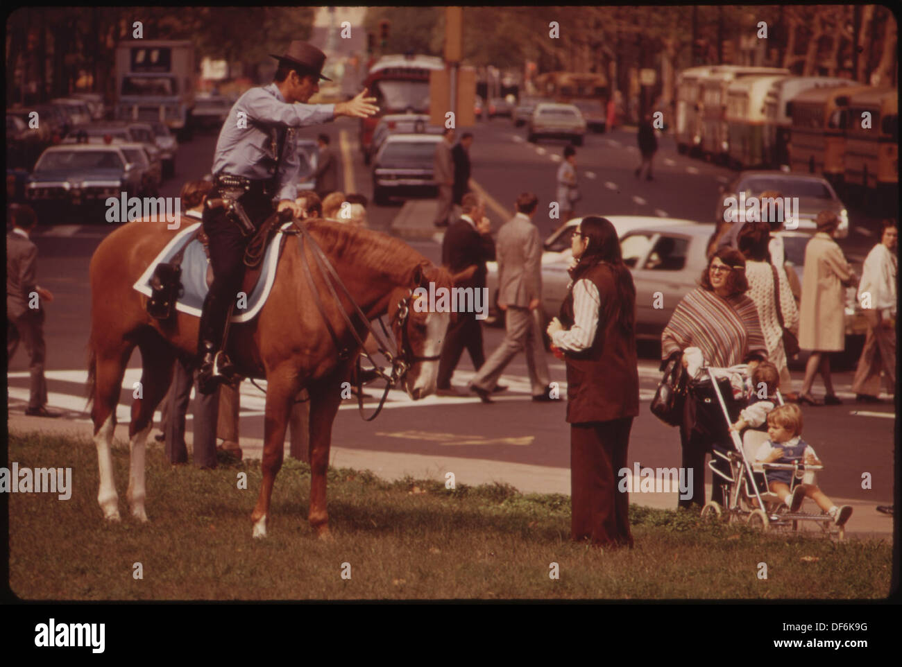 Un poliziotto a cavallo pattuglia una trafficata strada del centro, dimostrando la presenza delle forze dell'ordine e della pubblica sicurezza in un ambiente urbano. Foto Stock