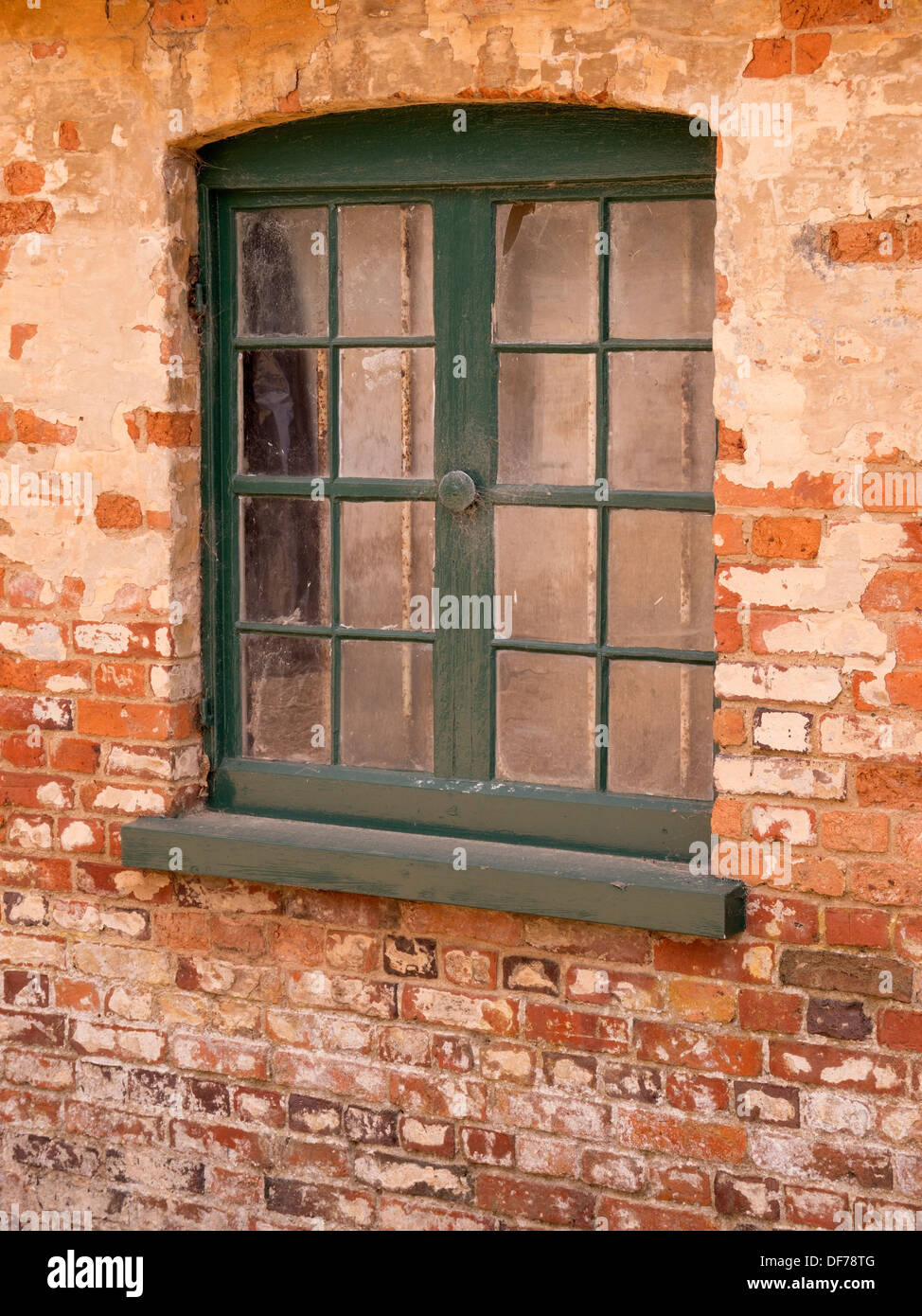 Vecchia finestra in legno verde con telaio verniciato impostato in rosso vecchio muro di mattoni, Ticknall, Derbyshire, England, Regno Unito Foto Stock