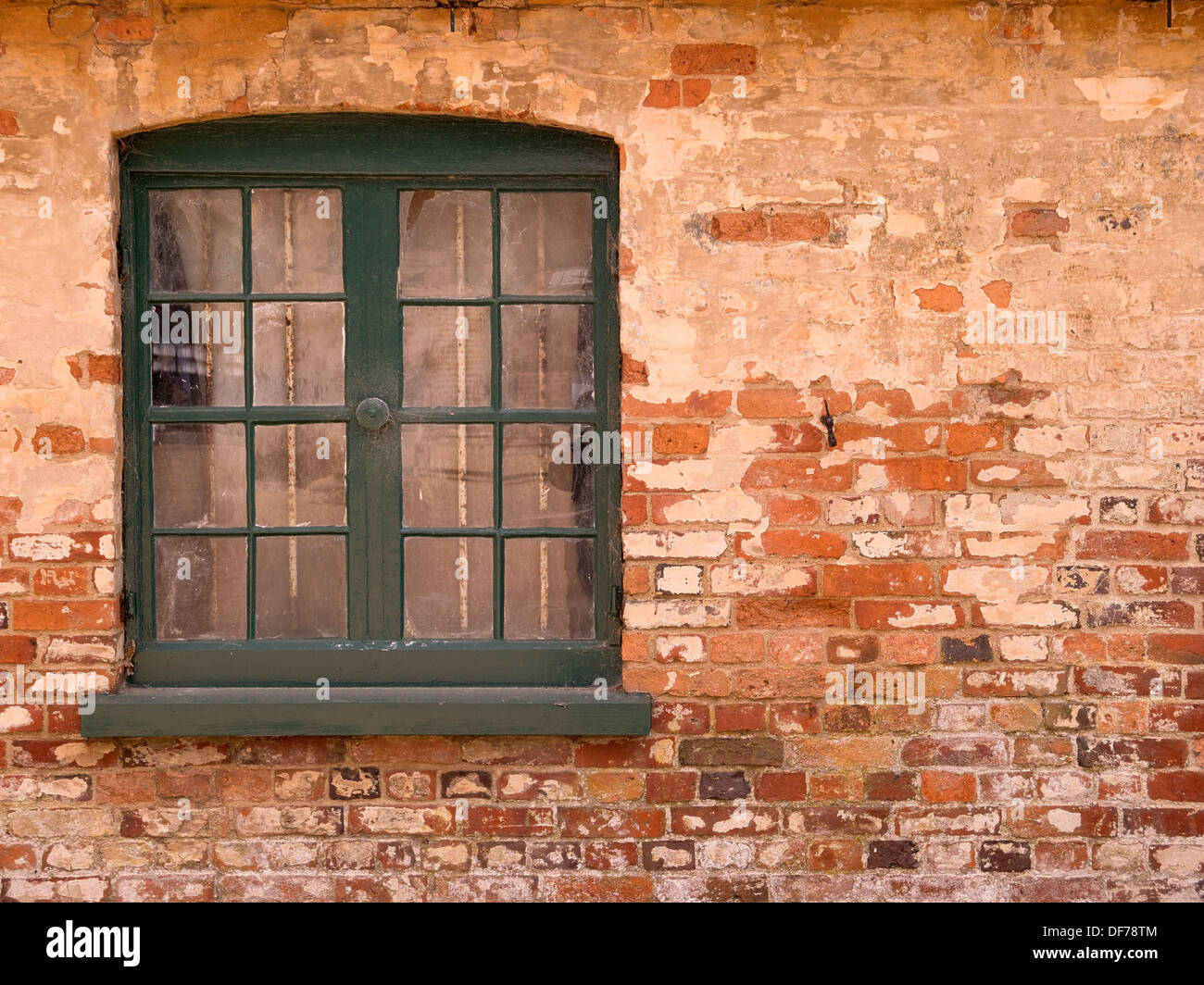 Vecchia finestra in legno verde con telaio verniciato impostato in rosso vecchio muro di mattoni, Ticknall, Derbyshire, England, Regno Unito Foto Stock