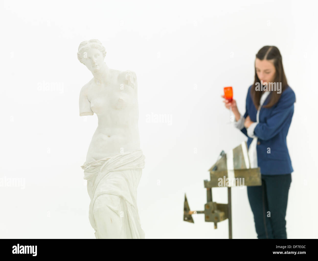 La donna a scrutare la scultura dietro una replica della Venere di Milo statua in un museo Foto Stock