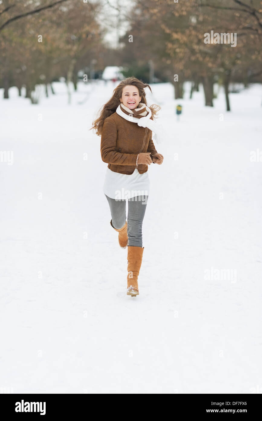 Felice giovane donna in esecuzione in winter park Foto Stock