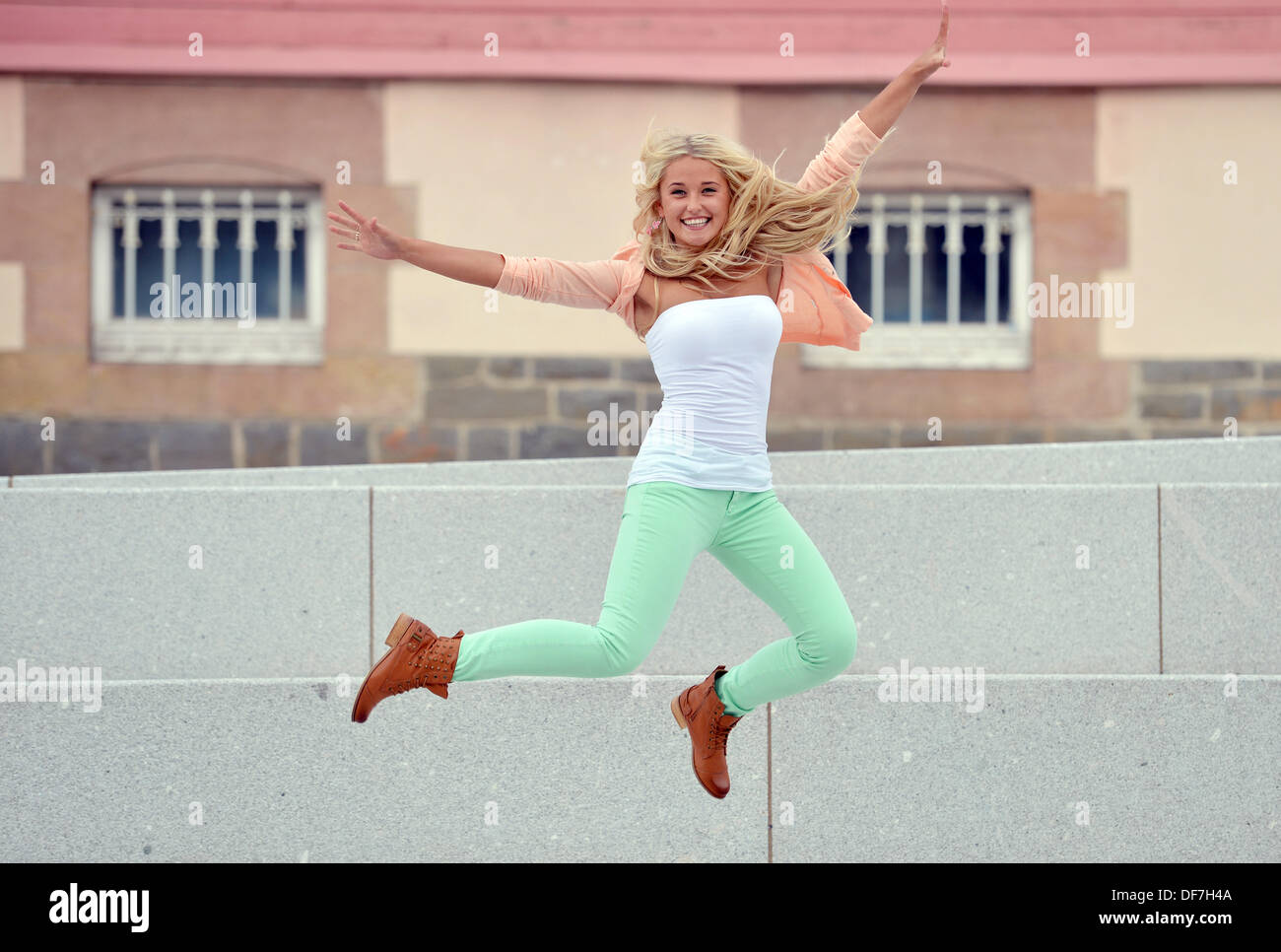 Una giovane donna bionda felicemente il salto. Foto Stock