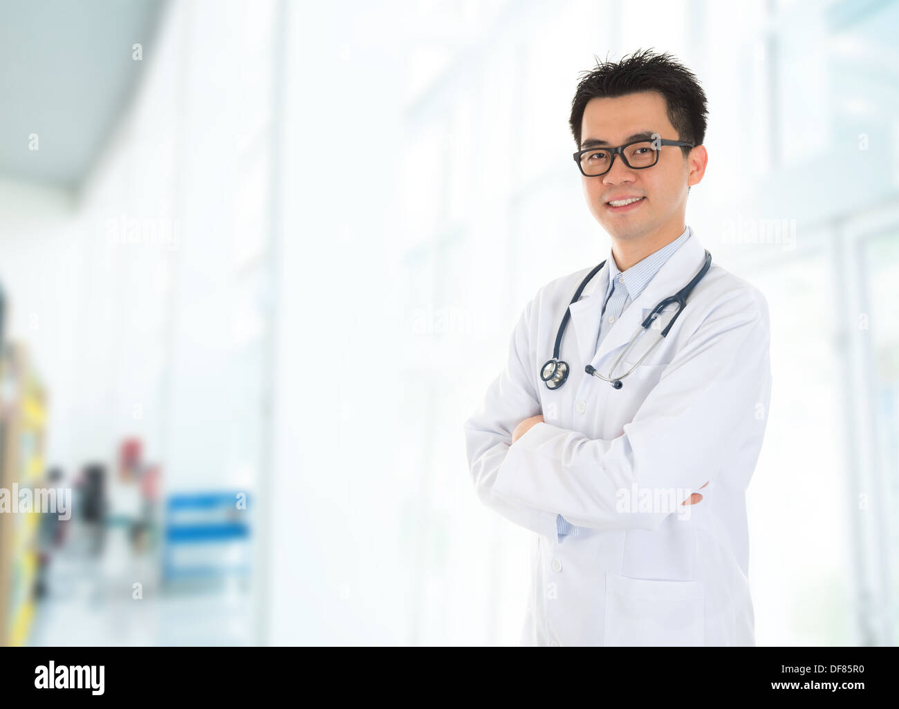 Maschio asiatici medico con sorriso sicuro in piedi all'interno di edificio dell ospedale. Foto Stock