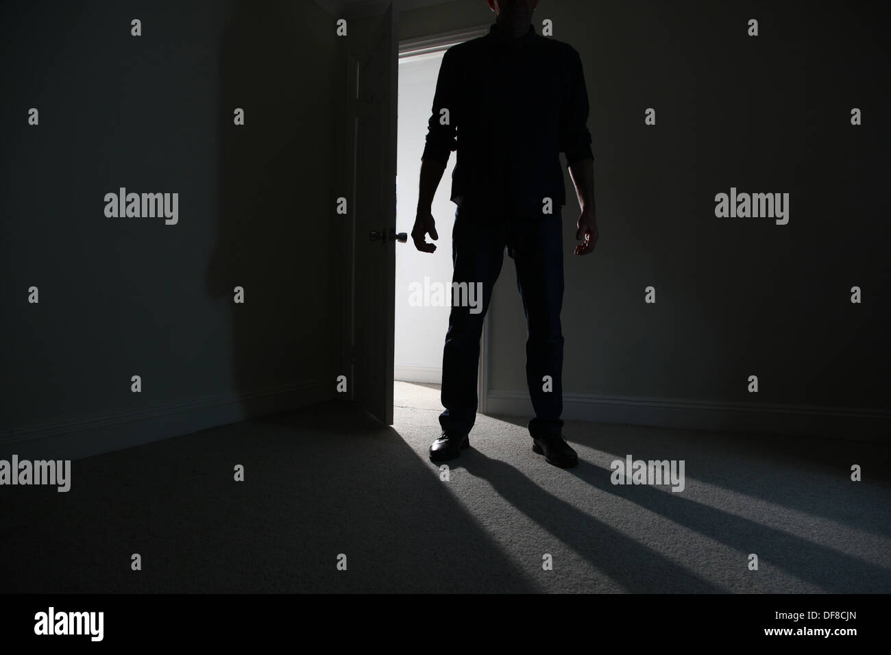 Silhouette di un maschio adulto in piedi in una porta aperta, entrando in una stanza buia. Modello rilasciato Foto Stock