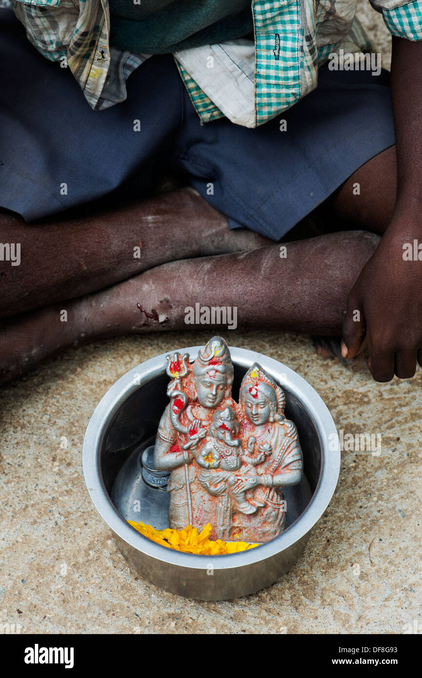 Scarsa bassa casta ragazzo indiano con la sua ciotola con una statua di shiva e pavarti in esso. Andhra Pradesh, India Foto Stock
