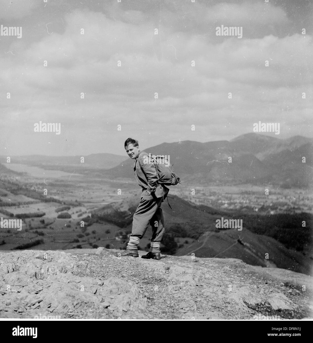 Quadro storico,anni cinquanta di un maschio di walker in tuta e back pack sulla sommità di una collina nel distretto del lago. Foto Stock