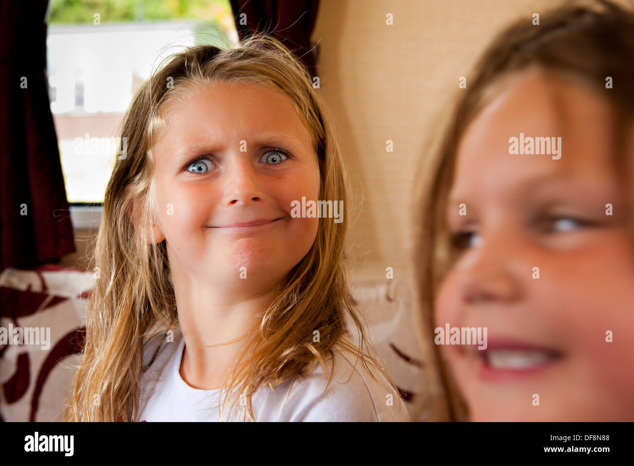 Sorelle e faccia buffa, profondità di messa a fuoco di campo ragazze sorridenti Foto Stock