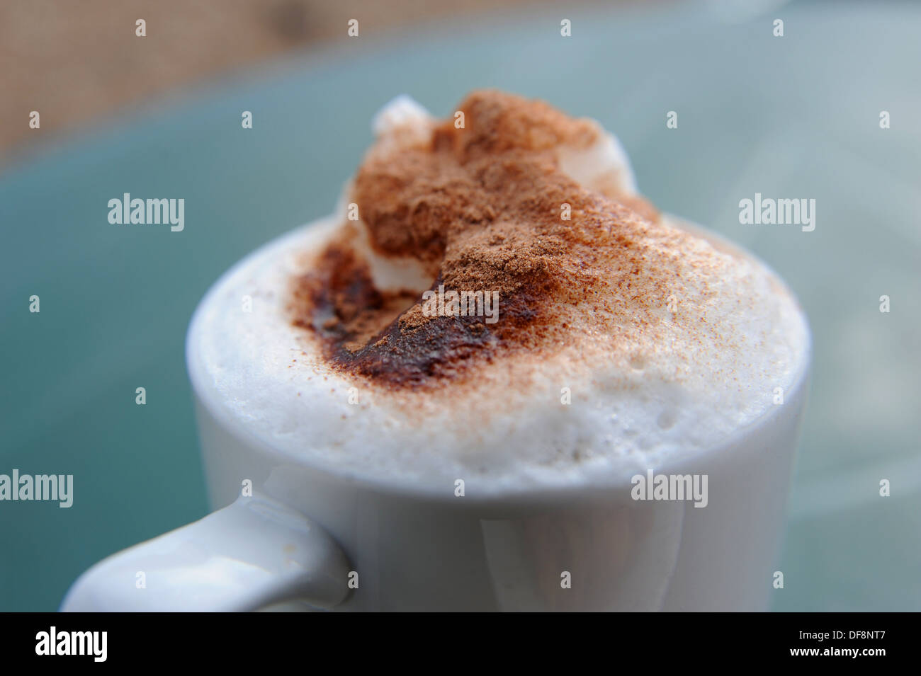 Caffè Cappuccino in una tazza e piattino con spuma di crema e cioccolato spruzza sulla parte superiore Foto Stock