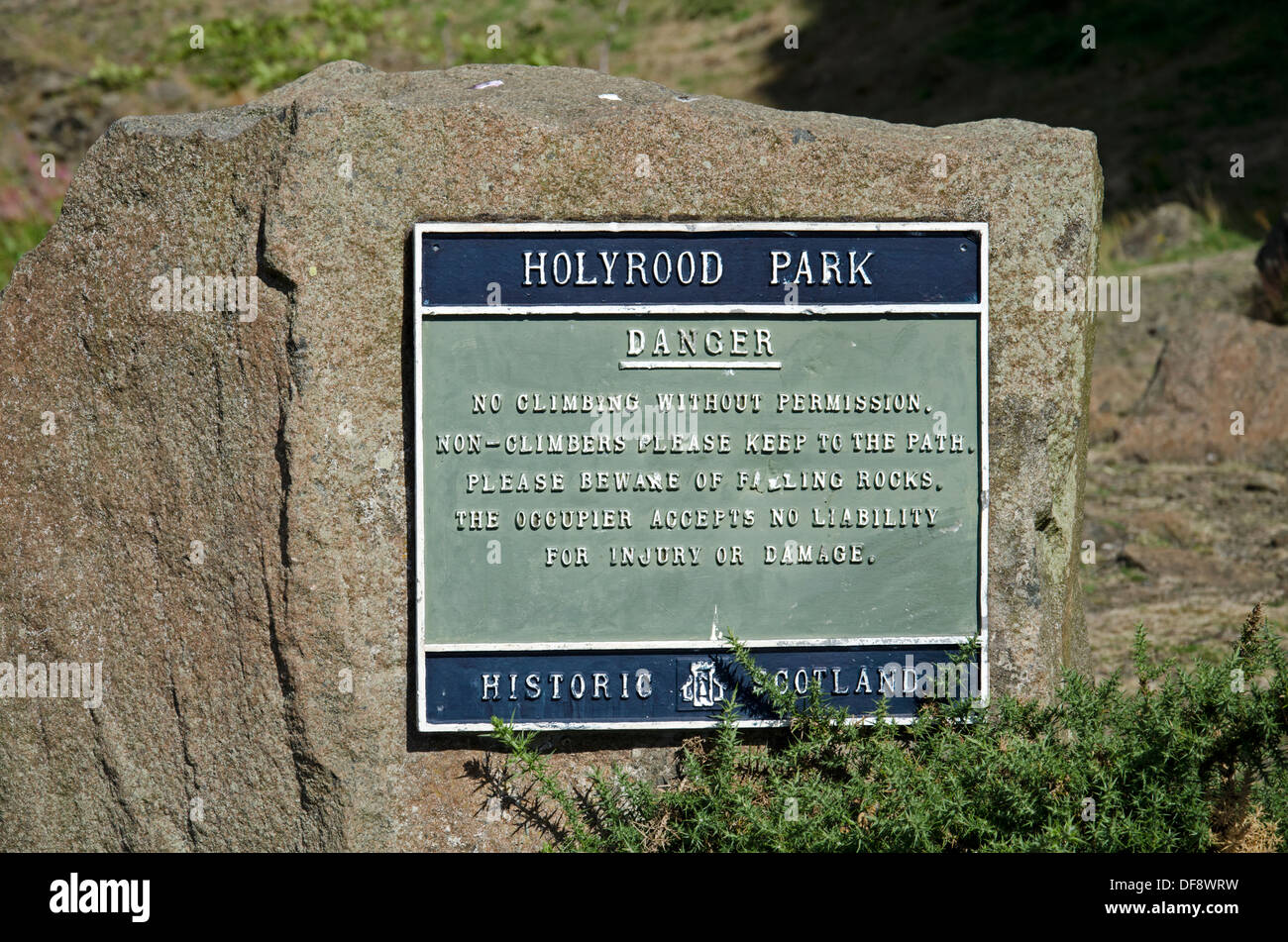 Un segno in Holyrood Park segnalazione di pericoli legati al fatto di salire sul vicino Salisbury Crags. Foto Stock